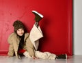 Cute asian kid girl in fashion oversize jacket and wide velvet pants is lying on the floor with her leg up over red Royalty Free Stock Photo