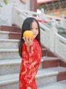 Cute asian kid girl in Traditional Chinese dress with holding sacred Orange at chinese temple in bangkok thailand, Chinese new