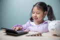 A cute Asian kid girl using calculator calculates for savings money. Concept to save money for education future. Ideas for tuition Royalty Free Stock Photo