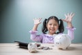 The cute Asian kid girl is very happy saving money to spend in the future with a piggy bank, stack coins, and calculator. Royalty Free Stock Photo