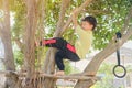 Cute Asian kindergarten boy child having fun facing challenge, trying to climb on the tree outdoor Royalty Free Stock Photo