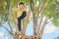 Cute Asian kindergarten boy child having fun facing challenge, trying to climb on the tree outdoor Royalty Free Stock Photo