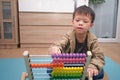 Cute asian kindergarten using the abacus with beads to learn how