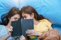 Cute Asian lesbian couple reading book together and lying on bed. Lifestyles and lovers concept. Happiness life and relax theme