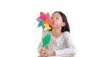 Cute Asian little child girl blowing colorful pinwheel isolated on white background. Kid hold and playing windmill in hand Royalty Free Stock Photo