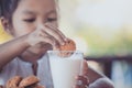 Cute asian little child girl eating cookie with milk Royalty Free Stock Photo