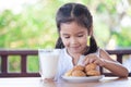 Cute asian little child girl eating cookie with milk Royalty Free Stock Photo