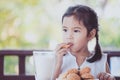 Cute asian little child girl eating cookie with milk Royalty Free Stock Photo