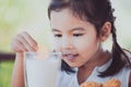 Cute asian little child girl eating cookie with milk Royalty Free Stock Photo