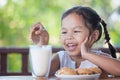 Cute asian little child girl eating cookie with milk Royalty Free Stock Photo