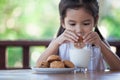 Cute asian little child girl eating cookie with milk Royalty Free Stock Photo