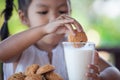 Cute asian little child girl eating cookie with milk Royalty Free Stock Photo