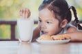 Cute asian little child girl eating cookie with milk Royalty Free Stock Photo