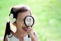 Cute asian little child girl looking through a magnifying glass Royalty Free Stock Photo