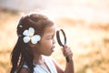 Cute asian little child girl looking through a magnifying glass Royalty Free Stock Photo