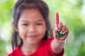 Asian little child girl with painted hands showing fingers number one