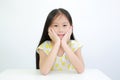 Cute Asian little child girl resting chin on hands on table over white background