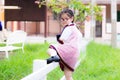 Cute Asian little child girl wearing a school uniform is climbing a white low fence to cross side to play on the playground.