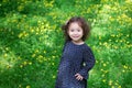 Cute asian little girl in black dress with white flowers and curly hair is enjoying sunny day in the park. Royalty Free Stock Photo