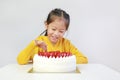 Cute asian little girl eating strawberry cake. Kid picking strawberries top of cake Royalty Free Stock Photo