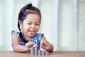 Cute asian little girl playing with coins making stacks of money Royalty Free Stock Photo