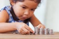 Cute asian little girl playing with coins making stacks of money Royalty Free Stock Photo