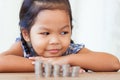 Cute asian little girl playing with coins making stacks of money Royalty Free Stock Photo