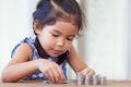 Cute asian little girl playing with coins making stacks of money Royalty Free Stock Photo