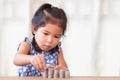 Cute asian little girl playing with coins making stacks of money Royalty Free Stock Photo