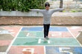 Cute Asian little girl playing hopscotch outdoor. Funny activity game for kids on the playground outside. Summer backyard street Royalty Free Stock Photo