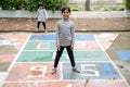 Cute Asian little girl playing hopscotch outdoor. Funny activity game for kids on the playground outside. Summer backyard street Royalty Free Stock Photo