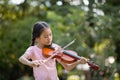 Cute Asian little girl playing the violin in the park Royalty Free Stock Photo