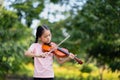 Cute Asian little girl playing the violin in the park Royalty Free Stock Photo
