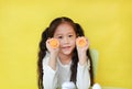 Cute asian little girl showing plastic eggs developmental puzzle isolated on yellow background