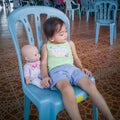 Cute Asian little girl sitting on a chair with her doll. outdoor, natural light Royalty Free Stock Photo