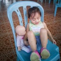 Cute Asian little girl sitting on a chair with her doll. outdoor, natural light Royalty Free Stock Photo