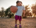 Cute Asian little girl in sportswear holding a basketball and looking at the camera at summer park. Healthy outdoor sport for Royalty Free Stock Photo