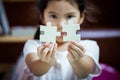 Cute asian little girl is trying to connect couple jigsaw puzzle Royalty Free Stock Photo