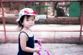 Cute Asian little girl walking in the zoo animal park and pushing the pink toy trolley. Wear a colorful white polka dot hat. Royalty Free Stock Photo