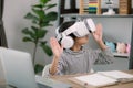 Cute Asian little girl wearing VR glasses with a laptop placed on the table in STEM technology class. Online education. Erudition