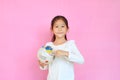 Cute asian little kid girl holding a globe with pointing United states at map on earth isolated over pink background. Portrait of Royalty Free Stock Photo