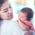 Asian newborn baby girl crying with tried on mother`s shoulder