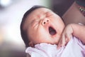 Cute asian newborn baby girl sleeping and yawning on mother`s arm Royalty Free Stock Photo