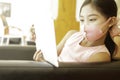A cute Asian schoolgirl at home, wearing a protection mask and learning online on a tablet.