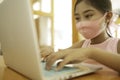A cute Asian schoolgirl wearing a mask is using a laptop to study online Royalty Free Stock Photo