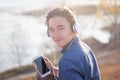 Cute Asian teen boy listening to music on headphones in his phone, smiling enjoying the view Royalty Free Stock Photo