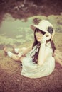 A cute Asian Thai girl is relaxing near the pond in the wilderness in vintage color