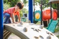 Cute Asian toddler child having fun trying to climb on artificial boulders at playground, Little boy climbing up a rock wall, Hand Royalty Free Stock Photo