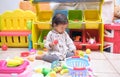 Cute Asian toddler girl child sitting on floor having fun playing alone in playroom at home, Little infant girl sitting W posture