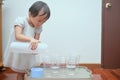 Cute Asian toddler girl having fun playing with water table at home, Wet Pouring Montessori Preschool Practical Life Activities,